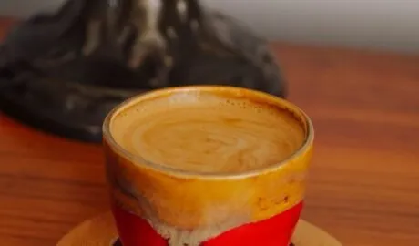 Boabe de cafea arabica și robusta alăturate lângă o ceașcă de espresso cu cremă